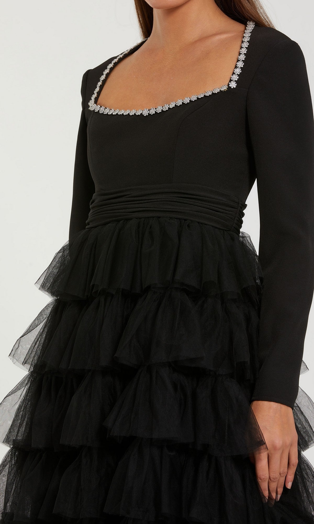 A woman wearing the Mac Duggal 27707 midi wedding guest dress—featuring long sleeves, a square neckline embellished with delicate floral accents, and a layered tulle skirt—a perfect modest choice for wedding guests. Only her upper body and part of the skirt are visible.
